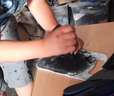 Klasse 2 - Steinzeit - Wohnen - Kohlestueck für Lagerfeuer zerkleinern
